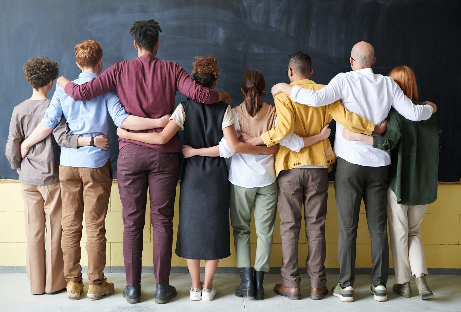 The Zigma team standing arm in arm facing a chalkboard wall